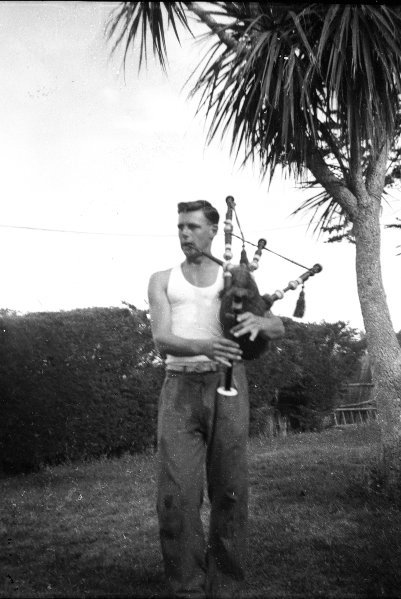Martin Palmer playing the bagpipes in front of thr old fram house Tairei Mouth